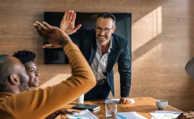 two colleagues celebrating success with a high five in the meeting room